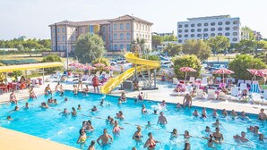 A swimming pool area with multiple lanes, a water slide, and lounge chairs.
