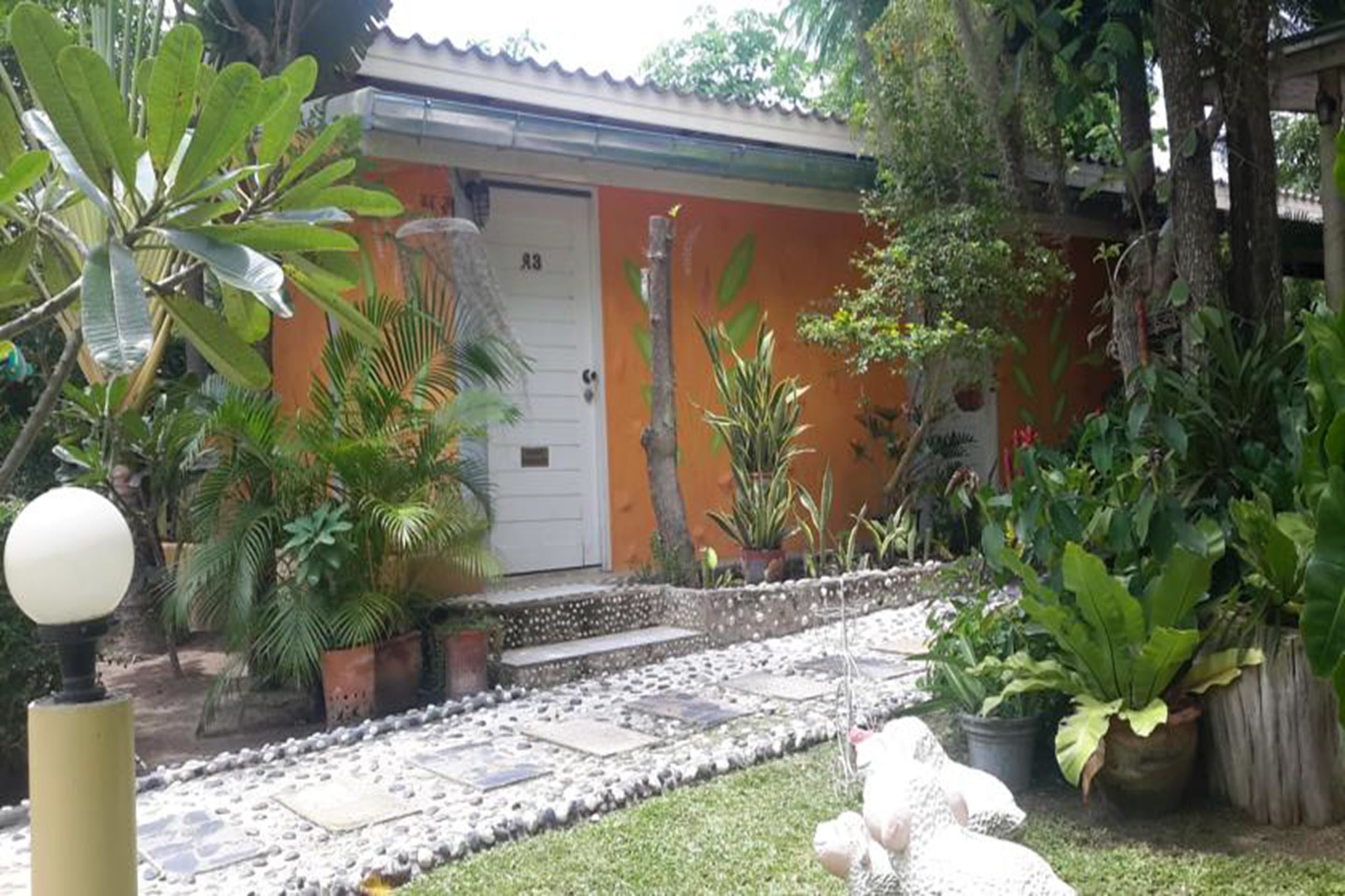 A house with a door labeled '3', surrounded by lush greenery and potted plants.