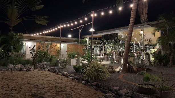Un complexe hôtelier doté d’une plage de sable, de palmiers et de guirlandes lumineuses.