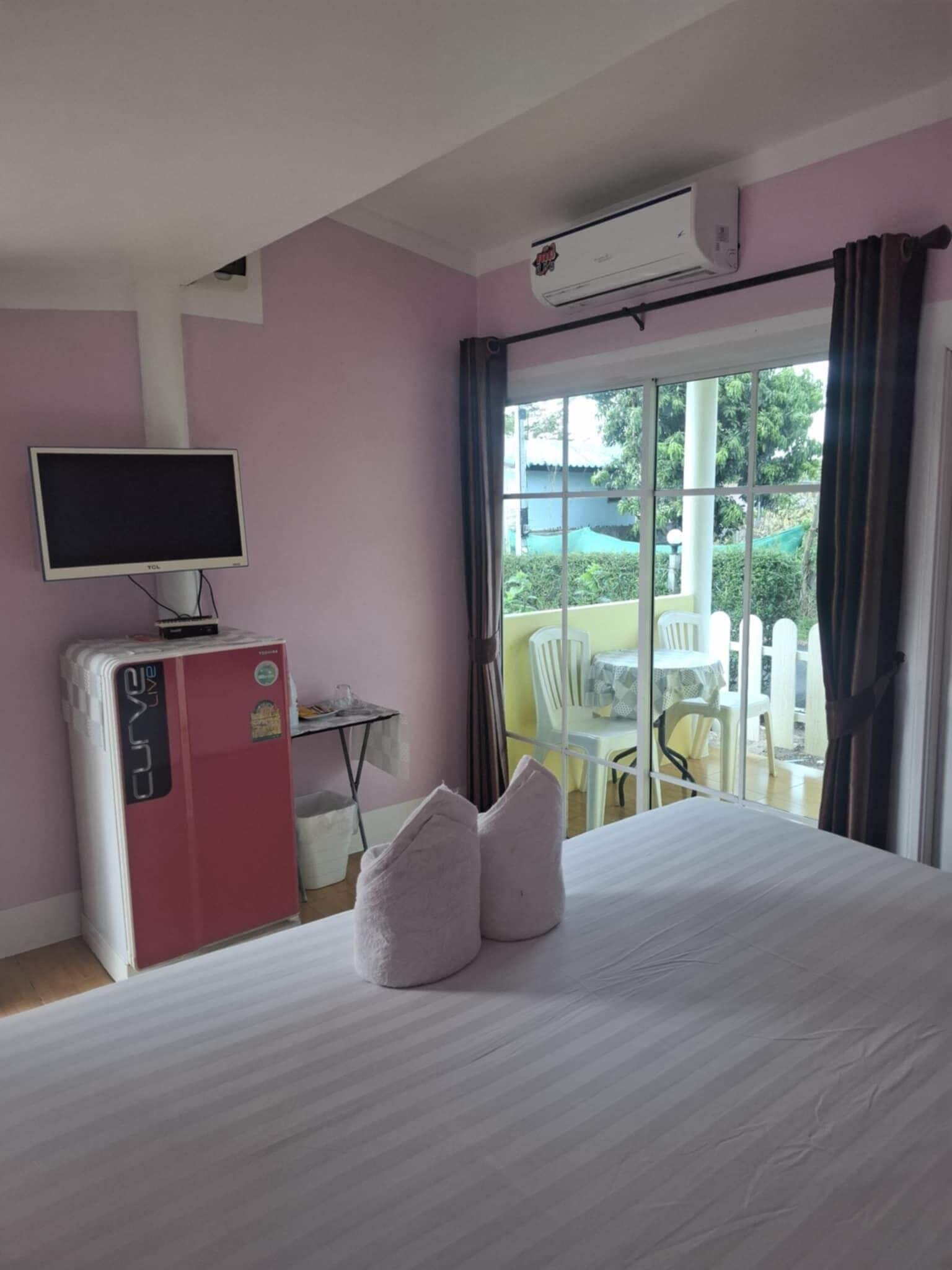 Une chambre d’hôtel équipée d’un lit, d’une télévision, d’un mini-réfrigérateur et d’un balcon avec des chaises et une table.