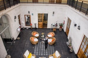 A courtyard with wicker furniture, a staff member, and a door leading to an interior space.