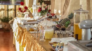 A buffet table with various food items, a pineapple centerpiece, and a pitcher of a yellow beverage. - Hotel Tikary (Arequipa)