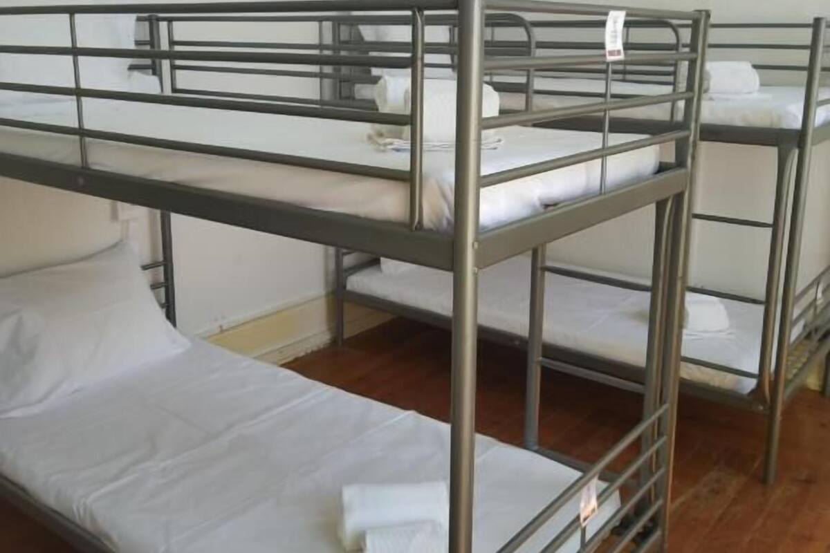 A dormitory room with bunk beds, a white lamp, and a wooden floor.