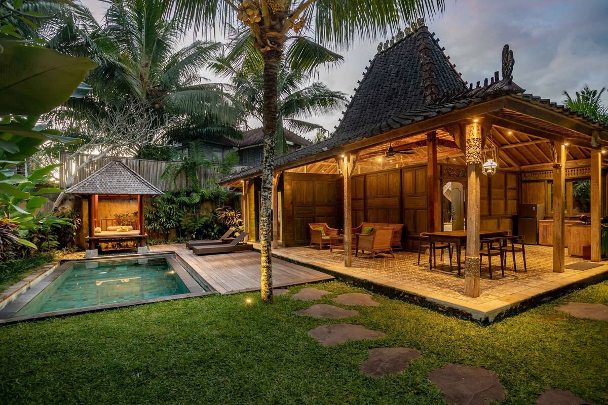 A wooden house with a pool, covered patio, and outdoor seating area.