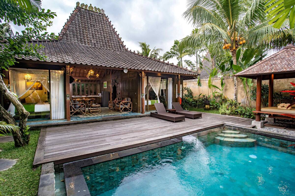 A traditional villa with a tiled roof, a wooden deck, and a swimming pool.