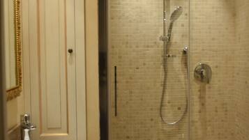 A bathroom with a glass-enclosed shower, a sink with a wine bottle and glass, and a mirror.