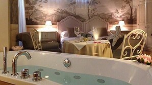 A luxurious hotel room with a large bathtub, a bed with a headboard, two bedside tables with lamps, and a wall mural. - La Corte Di Ambra (Cortona)