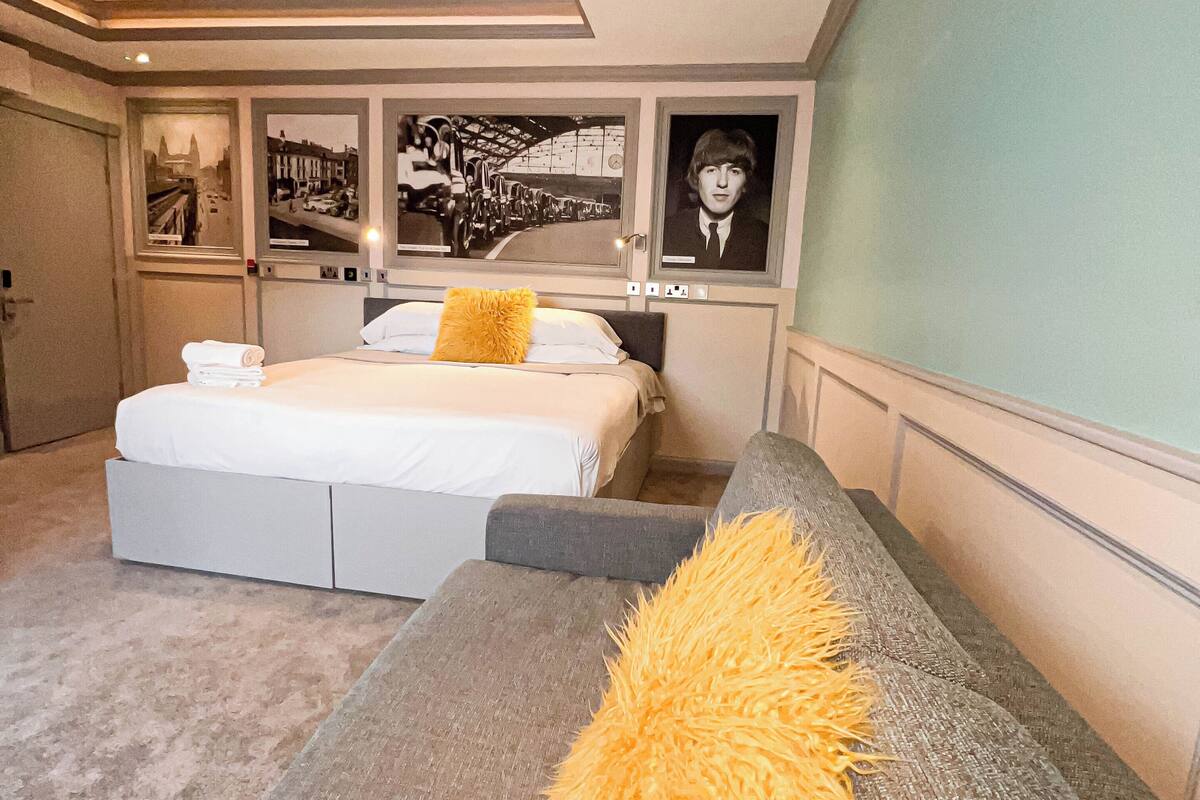 A modern bedroom with a large bed, a sofa, and artwork on the walls.