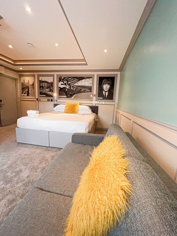 A modern bedroom with a large bed, a sofa, and artwork on the walls.