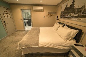 Habitación de hotel con cama, escritorio, teclado, teléfono y un cartel en la pared.