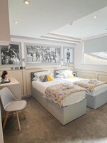 Habitación de hotel con cama, escritorio y silla. En la pared, tres cuadros enmarcados.