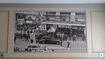 A black and white photo of a crowd in Lime St. with a car and a Beatles banner.