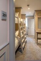 Habitación de hotel con literas, un baño con espejo y una puerta con la etiqueta '201'.