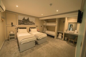 Una habitación de hotel con dos camas, un escritorio, un espejo y una litera.