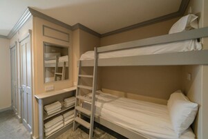 A bunk bed room with a built-in closet and a ladder.
