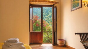 Une chambre d’hôtel avec un balcon, un lit avec des serviettes, un panier en osier et un tableau encadré au mur.