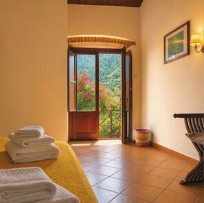 A hotel room with a balcony, a bed with towels, a wicker basket, and a framed picture on the wall. - Azienda Agrituristica Le Puzelle (Santa Severina)