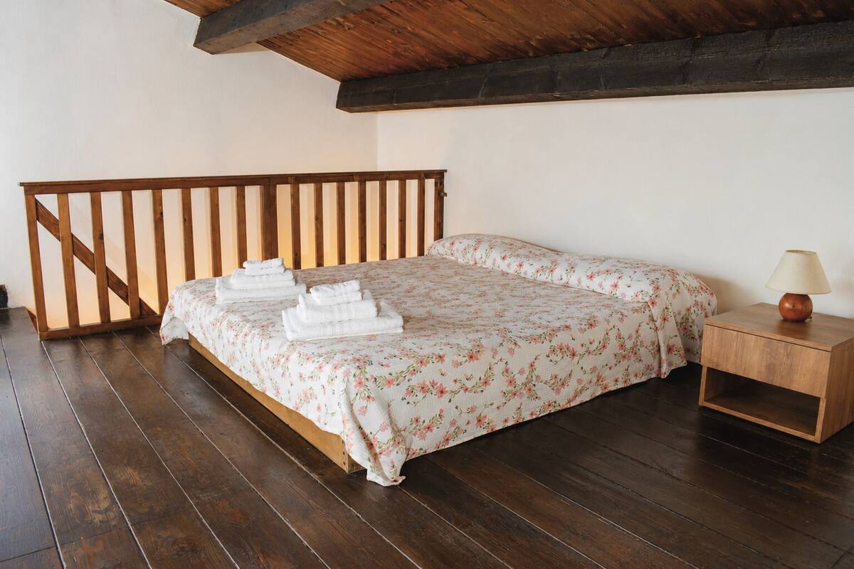 Ein Schlafzimmer mit einem hölzernen Bett, einem Nachttisch ebenfalls aus Holz und einem Holzgeländer.