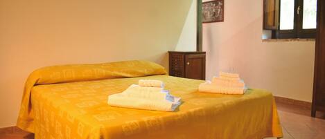Un lit simple avec une couvre-lit jaune et deux serviettes pliées posées dessus.