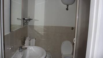 A bathroom with a sink, toilet, and a mirror.
