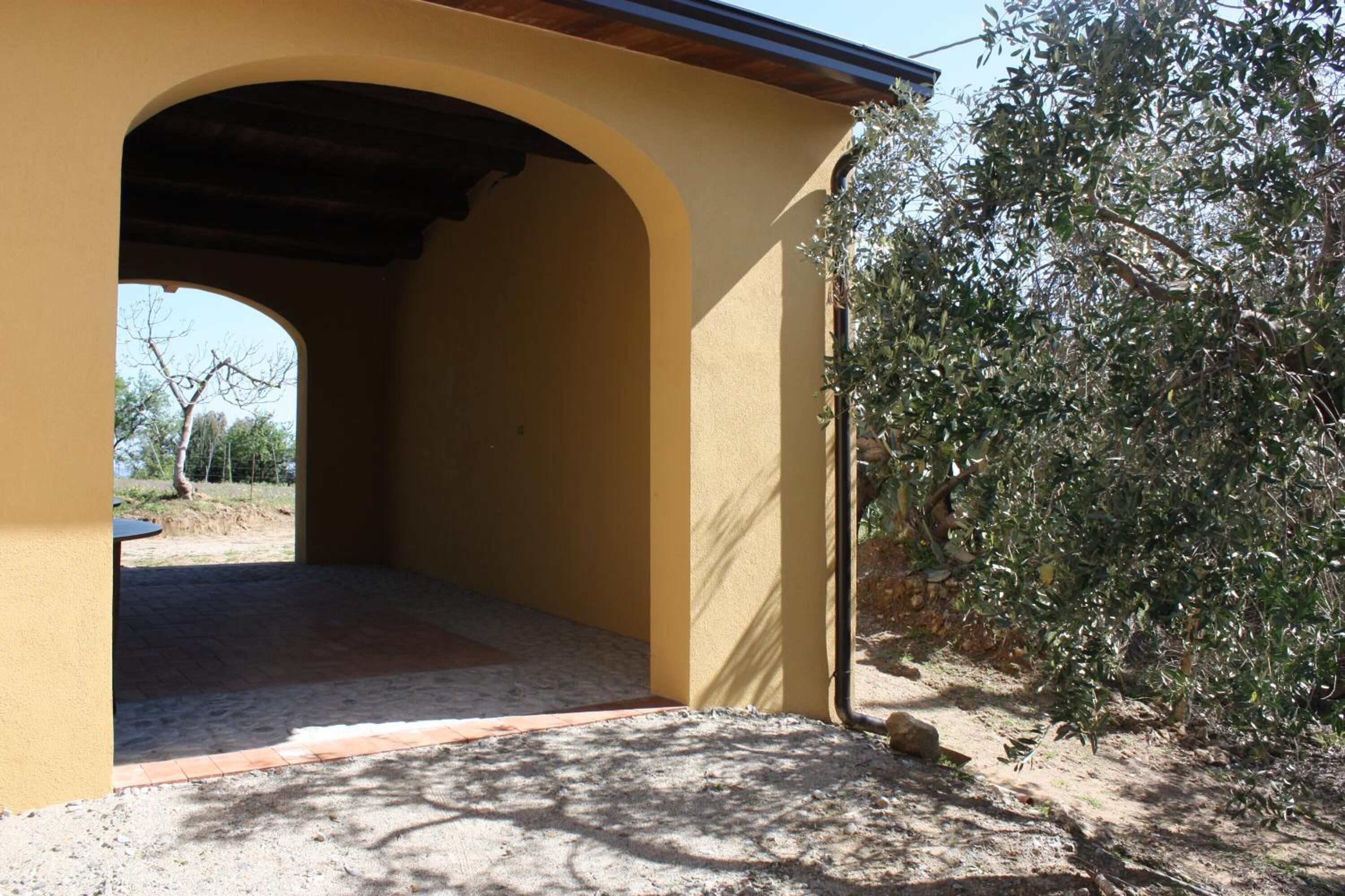 Un patio extérieur couvert, avec un mur jaune et une arche.
