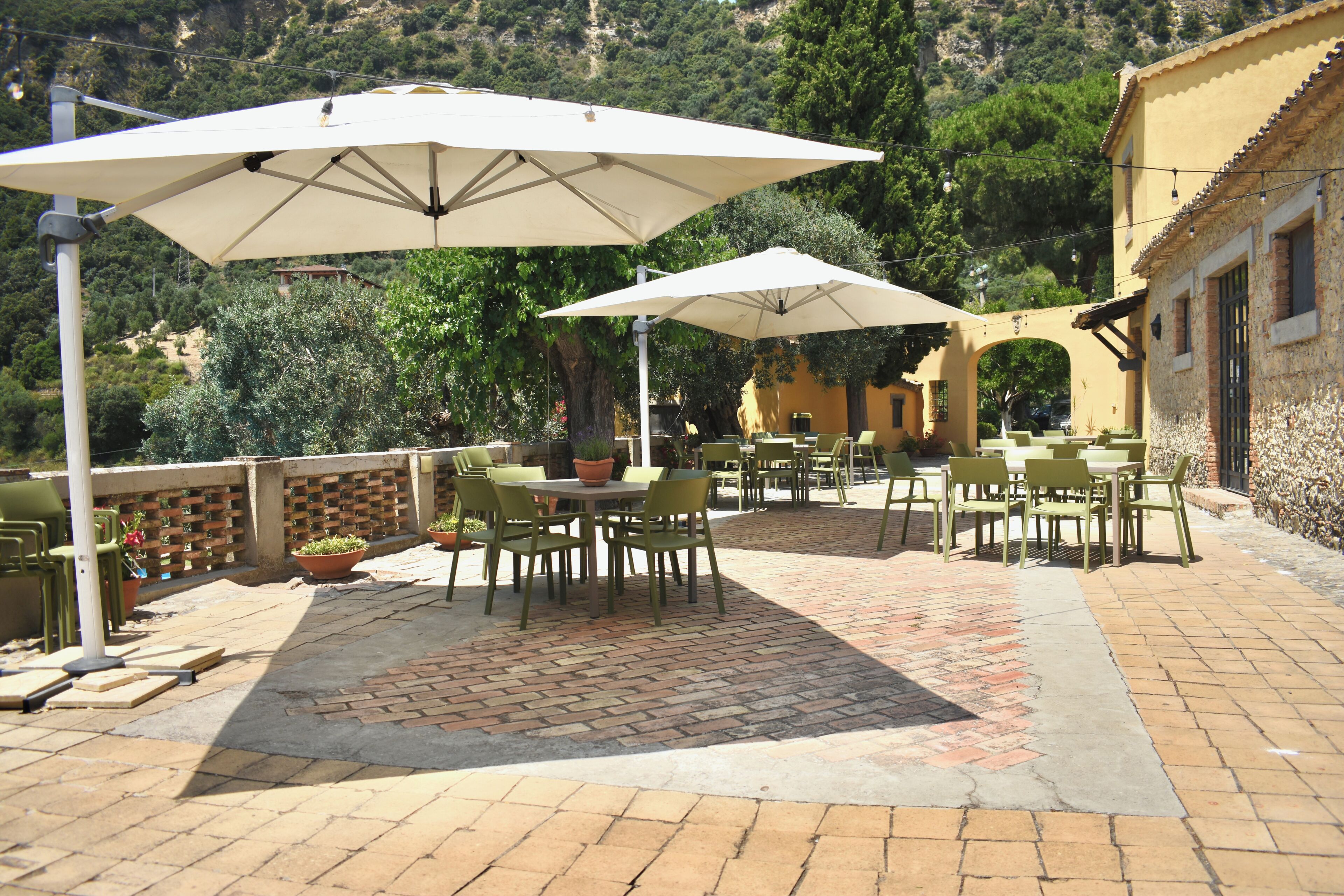 An outdoor patio with tables and chairs, umbrellas, and potted plants.