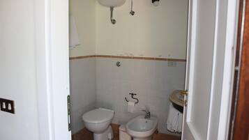 A small bathroom with a toilet, bidet, and sink.