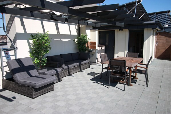 An outdoor patio with a sofa, chairs, and a table.