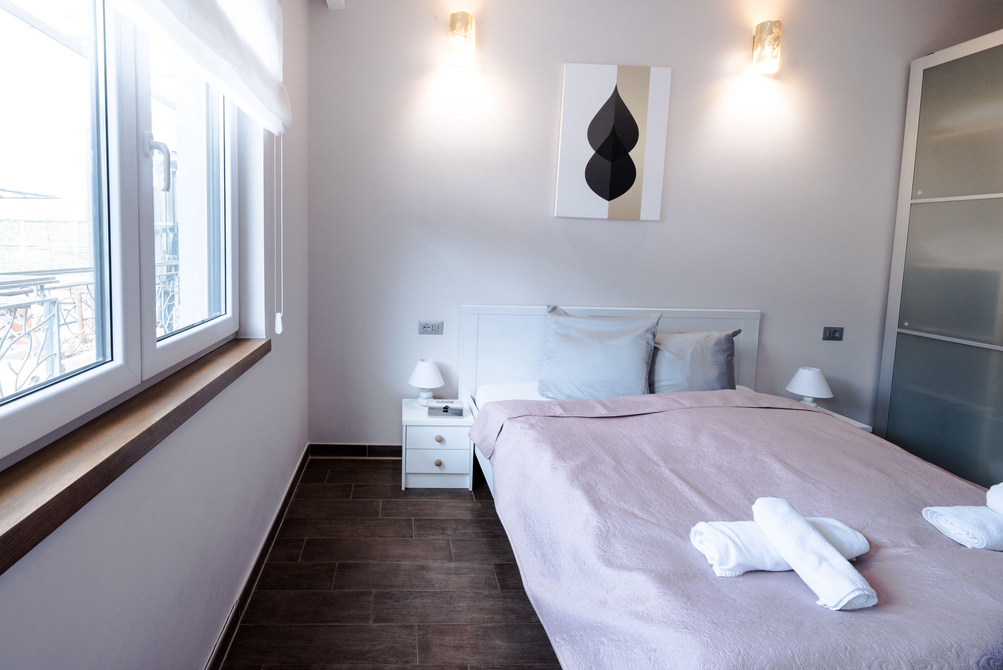 Ein modernes Hotelzimmer mit einem großen Bett, Nachttischlampen, einem Beistelltisch und einem Fenster mit Blick nach draußen.