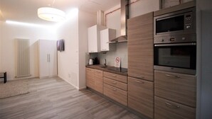 A modern kitchen with wooden cabinets, stainless steel appliances, and a built-in microwave. - Budapest Easy Flat - Teresa Lux Apartment (Budapest)