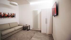 A modern living room with a sofa, a small table, a radiator, and a TV mounted on the wall. - Budapest Easy Flat - Teresa Lux Apartment (Budapest)