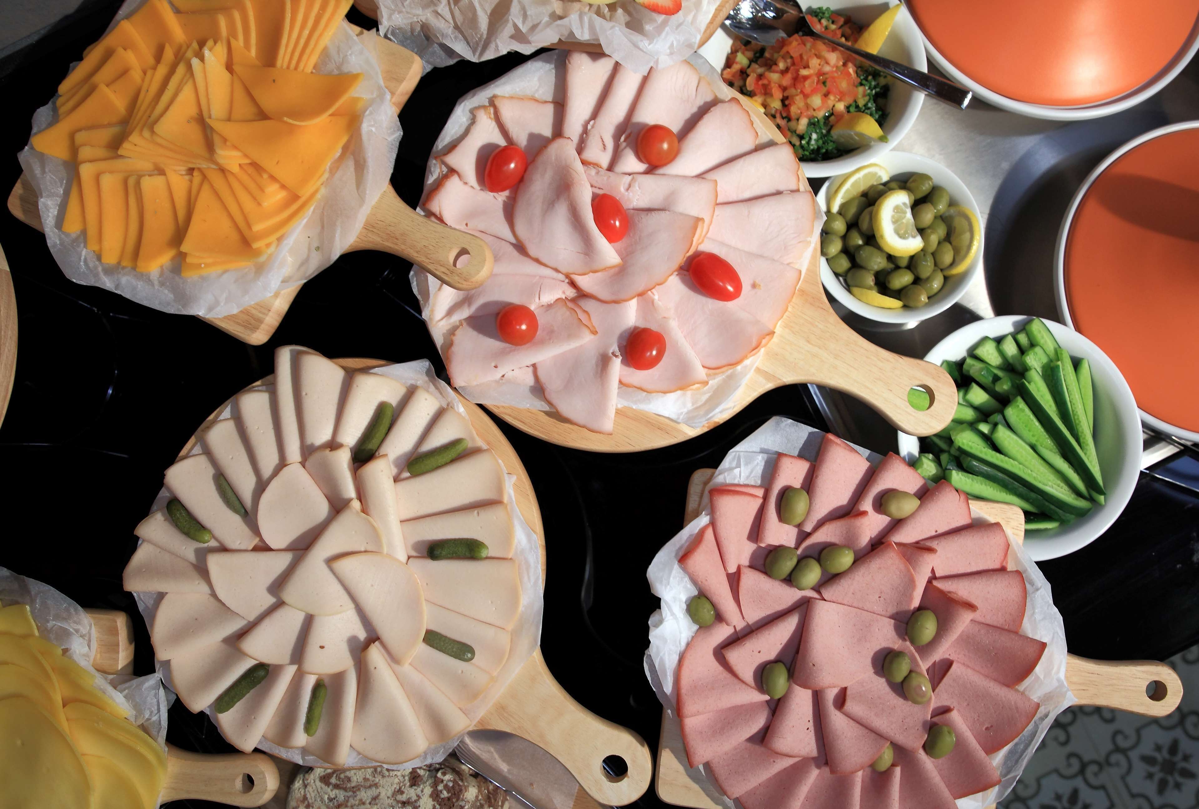 Diversos tipos de carnes fatiadas e queijos dispostos em tábuas de madeira.