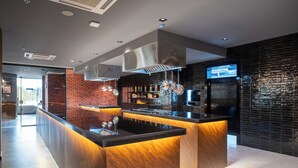 Uma cozinha moderna com ilha central, eletrodomésticos de aço inoxidável e parede decorada com tijolos.