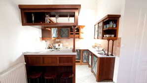 A kitchen with wooden bar stools, a white countertop, and a tiled backsplash. - Budapest Easy Flat - Wesselenyi Apartment (Budapest)