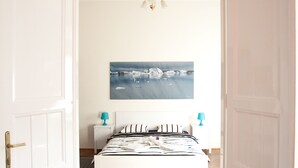 A bedroom with a wooden parquet floor, a white bed with striped bedding, two bedside tables with lamps, and a painting on the wall. - Budapest Easy Flat - Wesselenyi Apartment (Budapest)