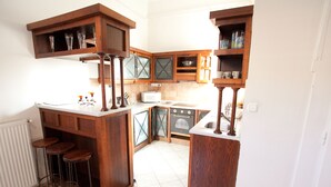 A kitchen with wooden cabinets, a white countertop, a microwave, and a stove. There are three stools under the counter. - Budapest Easy Flat - Wesselenyi Apartment (Budapest)
