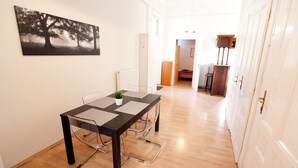 A dining area with a table and chairs, a radiator, and a painting of trees on the wall. - Budapest Easy Flat - Wesselenyi Apartment (Budapest)