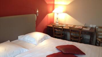 A hotel room with a bed, a desk, and two chairs.