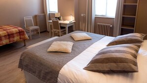 Une chambre d’hôtel équipée d’un lit, d’un bureau, d’une chaise et d’un téléviseur fixé au mur.