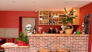 Un coin bar avec un comptoir en briques, deux tabourets, une variété de bouteilles, des verres et une plante en pot.