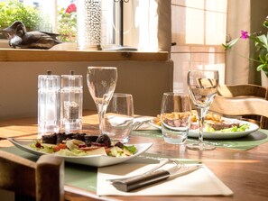 Une table à manger avec des assiettes remplies de nourriture, des verres et des salières.