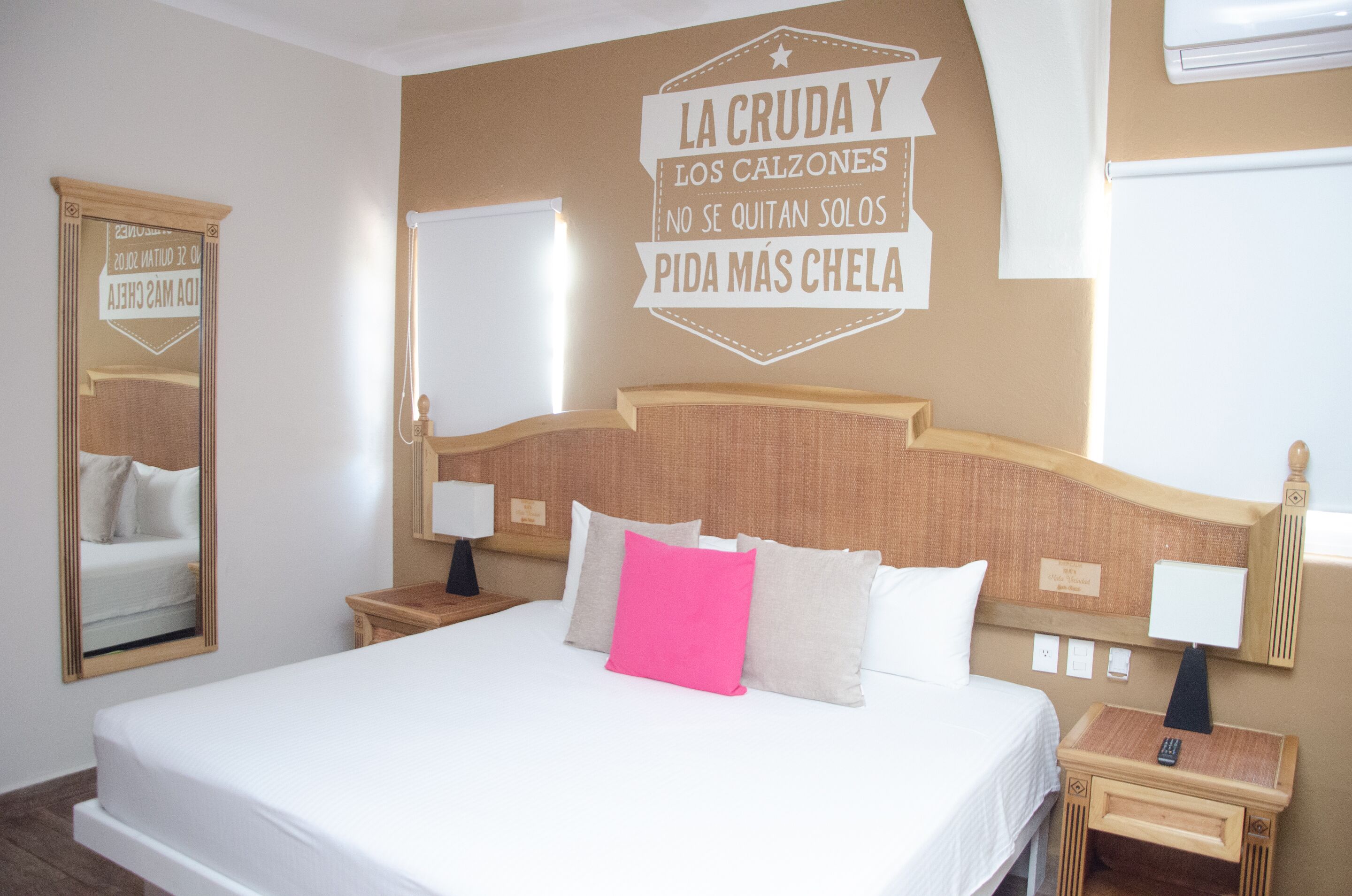 A hotel room with a large bed, two bedside tables, a mirror, and a wall decoration.