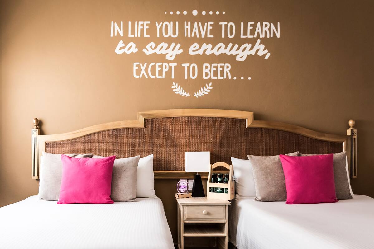 Een hotelkamer met twee bedden, een nachtkastje en een muisbrief.