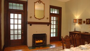 Uma sala de jantar com lareira, portas de madeira e uma mesa posta para quatro pessoas.