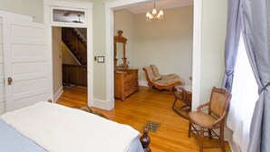 Quarto com cama, penteadeira, cadeira e escada que leva a outro cômodo.