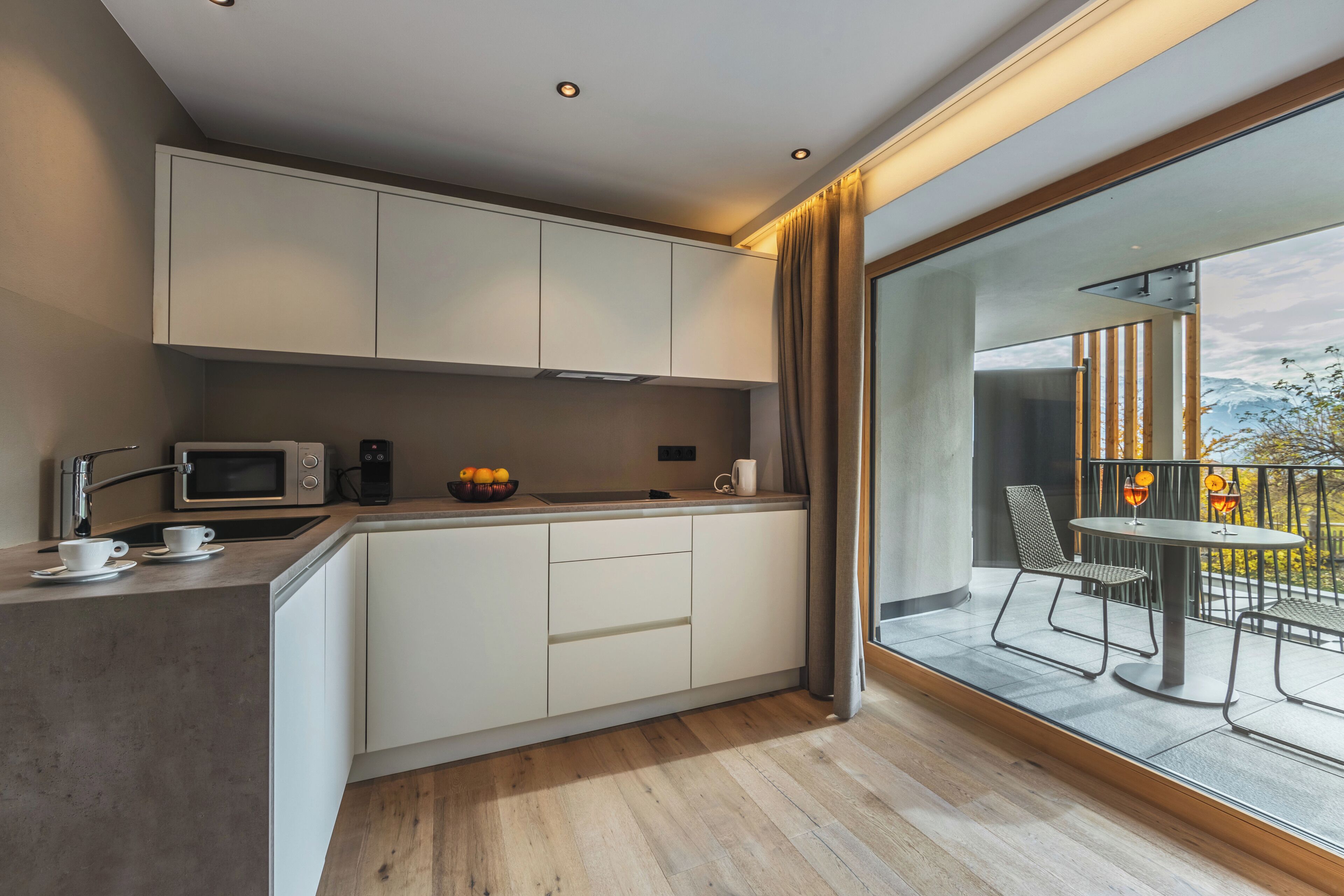 A modern kitchen with white cabinets, a microwave, and a dining area with a table and chairs.