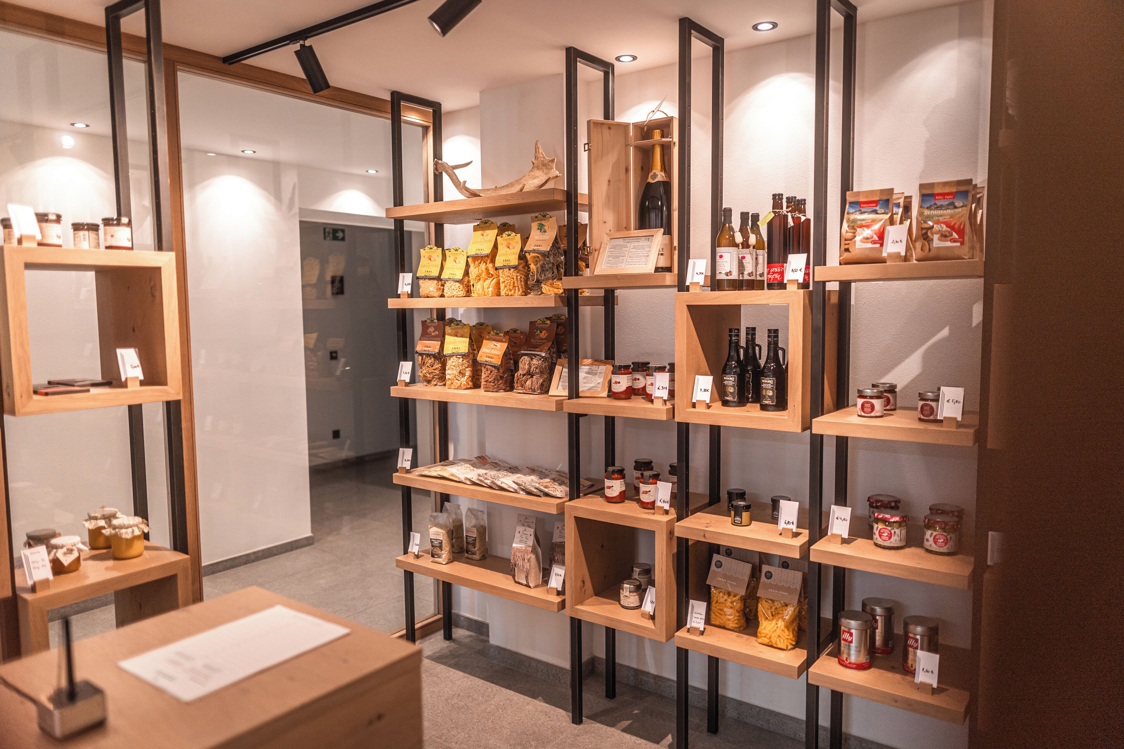 Una tienda con estantes de madera que exhiben diversos productos y alimentos.