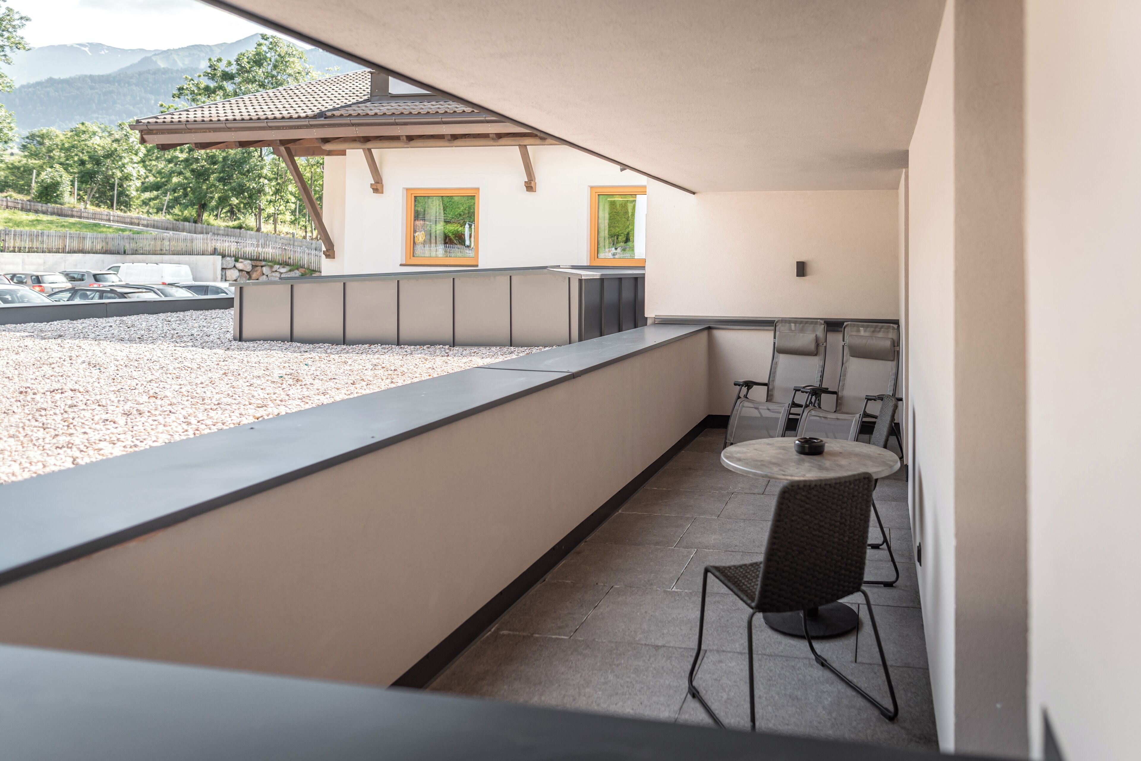 Un balcón con zona de estar, una mesa y sillas, y vistas a un edificio con ventanas.