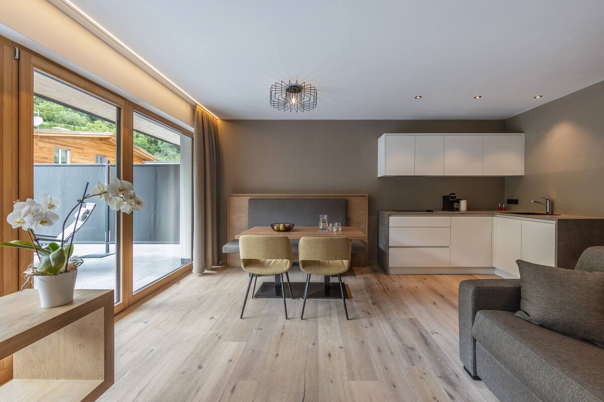 Un salon moderne comprenant un canapé, une table à manger avec des chaises et un coin cuisine avec des placards et un plan de travail.