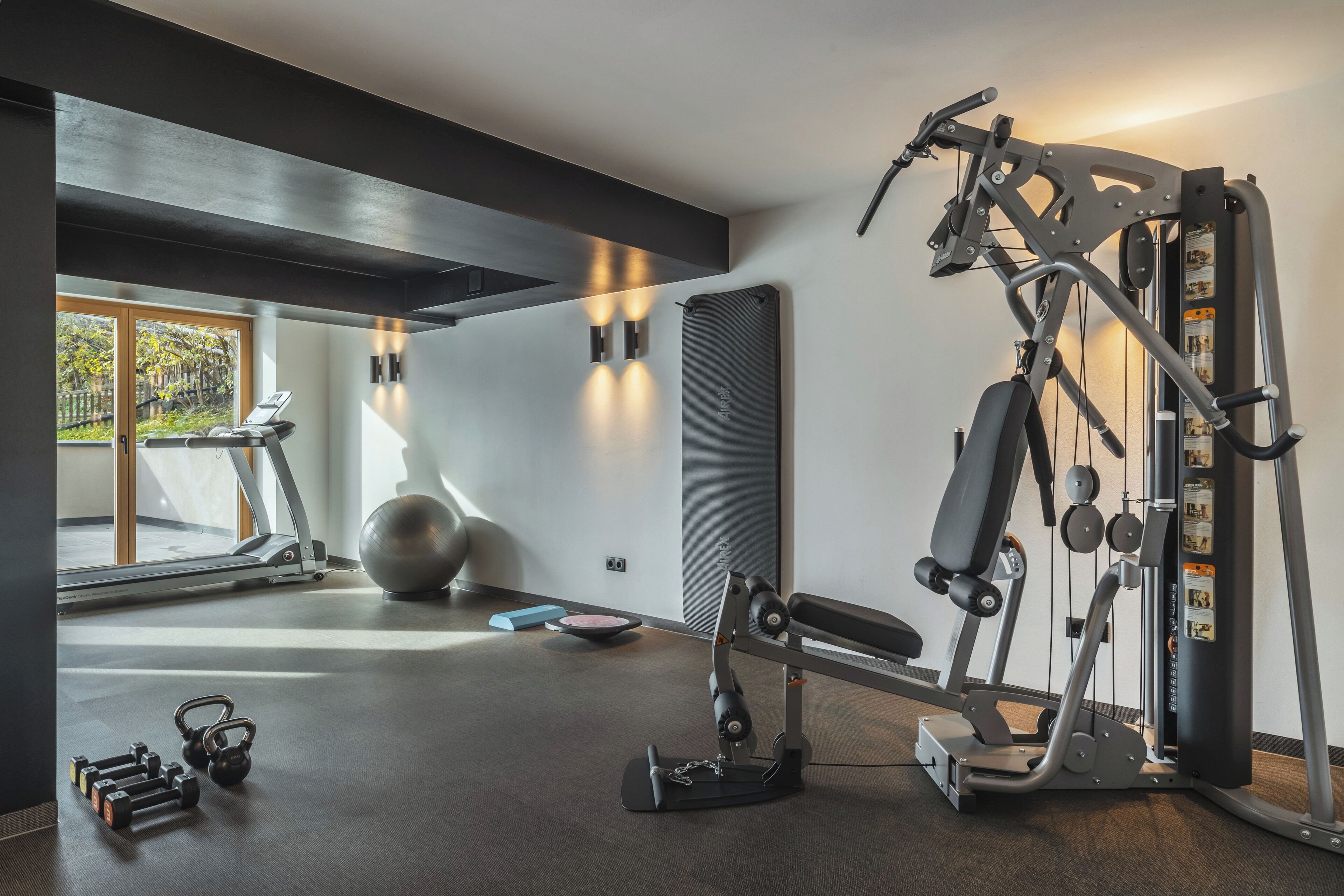 Un gimnasio con cinta de correr, pelotas de ejercicio y máquinas de pesas.